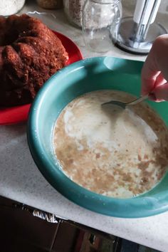 a person is spooning milk into a bowl next to a cake on a plate