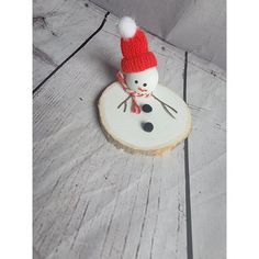 a small snowman is sitting on top of a piece of wood