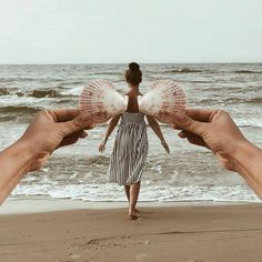 two hands holding a doll in front of the ocean