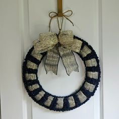 a knitted wreath hanging on the front door with two bow ties attached to it