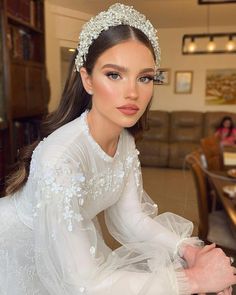 a woman wearing a white dress and tiara sitting at a table in a restaurant