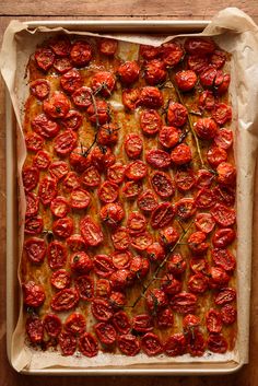 a baking pan filled with cooked tomatoes on top of a wooden table