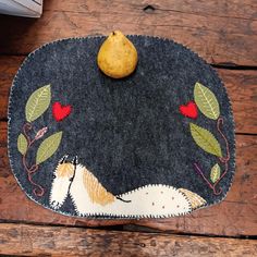 a pear sitting on top of a table next to a piece of cloth with animals and leaves