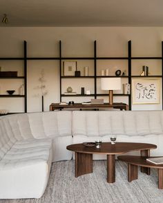 a living room with a white sectional couch and coffee table in front of a bookshelf