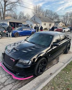 a black car with pink trim parked on the street