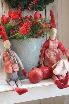 two dolls are sitting on a shelf next to some flowers and an old tin can