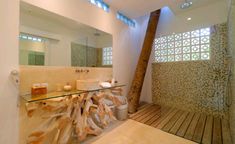 a bathroom with a glass counter top next to a wooden floor and a large mirror