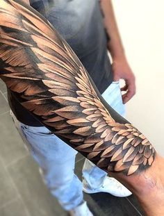 a man's arm with an intricate wing tattoo design on the left forearm and right leg