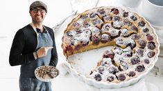 a man standing next to a pie on top of a white table with a slice missing from it