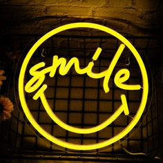 a smile neon sign hanging from the side of a brick wall