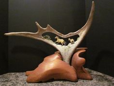 a wooden sculpture with animals on top of it's antlers and in the background is a black wall