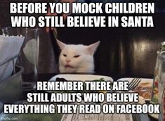 a white cat sitting at a table in front of a book with the caption before you mook children who still believe in santa