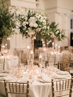 an elegant wedding reception with tall centerpieces and white flowers on the top table