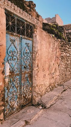 an old building with a blue door on the outside and stone walls in front of it