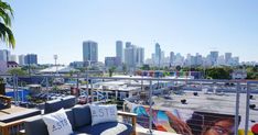 an outdoor seating area with city skyline in the backgroung and palm trees