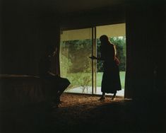 a woman standing in front of an open door with her hand on the glass,