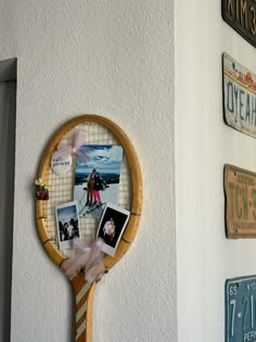 a tennis racket hanging on the wall with pictures and magnets attached to it