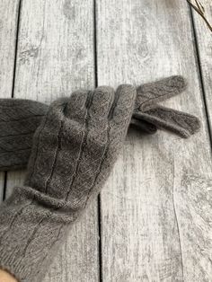 a pair of gray gloves sitting on top of a wooden floor