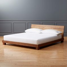 the bed is made up and ready to be slept in it's natural wood frame