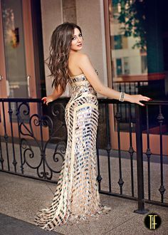 a beautiful woman in a long dress leaning on a railing