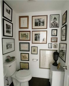 a white toilet sitting in a bathroom next to a wall with pictures on it's walls