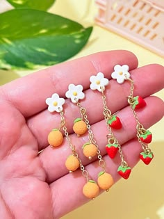 the small fruit charms are on display in someone's hand, with flowers hanging from them