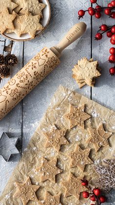 some cookies are laying out on the table next to a rolling pin and christmas decorations