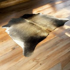 a brown and white cowhide rug sitting on top of a wooden floor