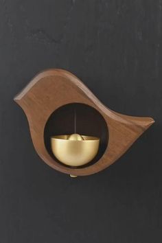 a wooden wall light with a gold bowl on the front and side, mounted to a black wall