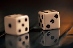 two white dices sitting on top of a glass table next to each other with black dots