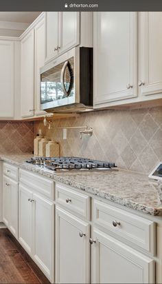 a kitchen with white cabinets and marble counter tops is seen in this image from the front view