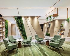 the interior of a library with green chairs and plants growing on the bookshelves