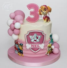 a pink and white birthday cake with paw patrol characters on the top, surrounded by balloons