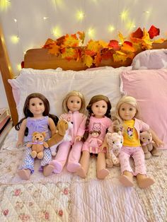 four dolls are sitting on the bed with their teddy bears