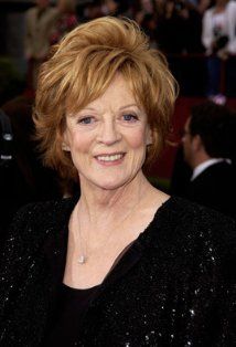 an older woman with red hair and blue eyes smiles at the camera while standing in front of a crowd