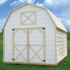 a large white barn sitting on top of a lush green field next to a blue sky