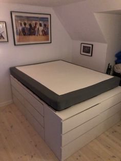 a bed with a mattress on top of it in a room next to pictures and paintings