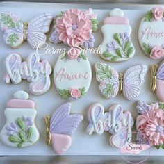 decorated cookies in the shape of baby's first names and flowers on a tray