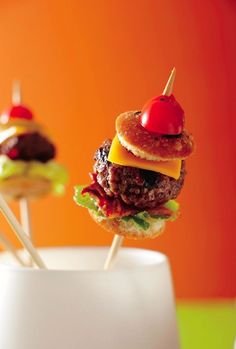 two hamburgers with toothpicks on them sitting in a cup