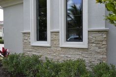 a white car is parked in front of a house with two windows that are facing each other