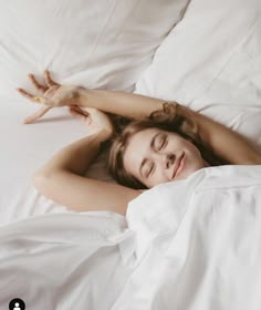 a woman is laying in bed with her eyes closed and hands up above her head