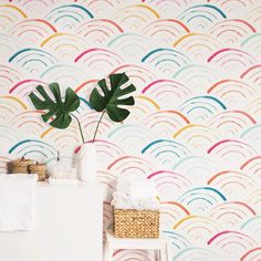 a bathroom with colorful wallpaper and a monster plant in the corner next to it