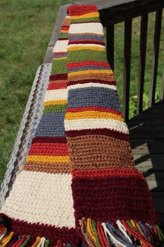 a multicolored crocheted blanket sitting on top of a wooden bench