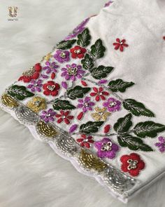 an embroidered piece of cloth with flowers and leaves on white furnishing, close up