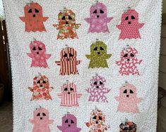 a quilt made to look like some little ghostes are hanging on the clothes line