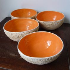 four orange bowls sitting on top of a wooden table