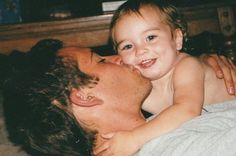 a man laying on top of a bed holding a small child