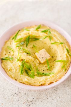 a bowl filled with mashed potatoes and topped with green garnish on top