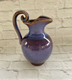 a purple vase sitting on top of a white brick wall