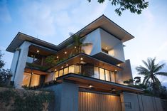 a large modern house with lots of windows and plants on the roof, along with palm trees